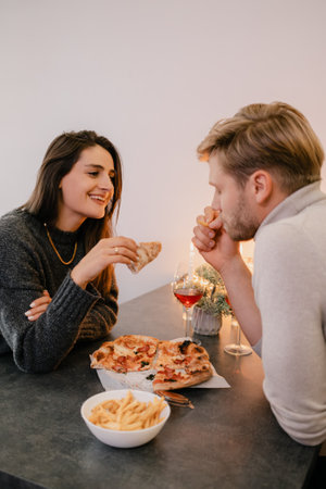 Couple enjoys pizza and wine at a cozy evening dinner settingの写真素材