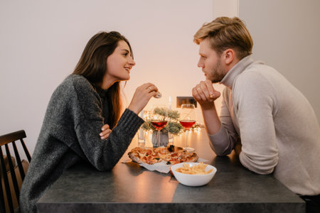 Happy couple enjoying dinner together with wine and holiday decorationsの写真素材