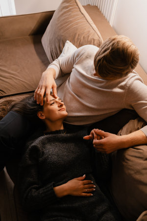 Couple sharing an intimate moment on a cozy couch with warm lightingの写真素材