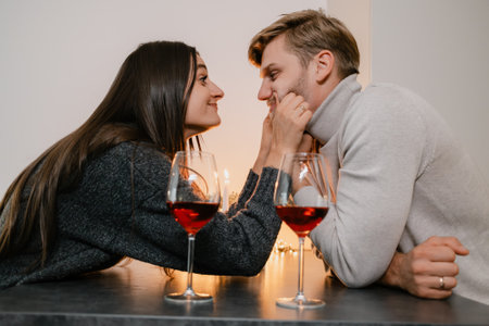 Couple enjoying romantic evening with candles and wine at a cozy tableの写真素材