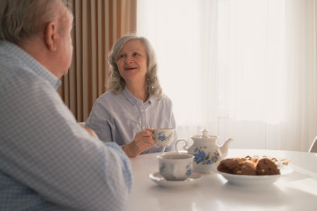 Elderly couple enjoying tea time together in a cozy and bright settingの写真素材