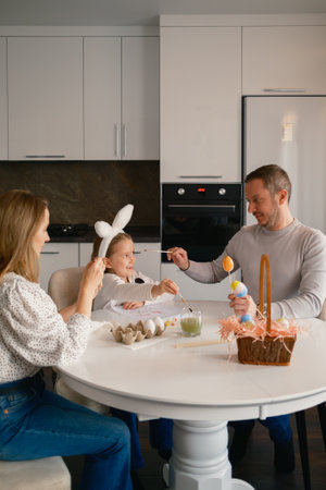 Family painting Easter eggs together at a kitchen table for the holiday