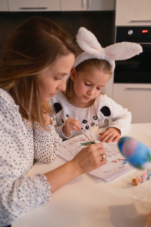Mother and daughter painting Easter-themed crafts together at home