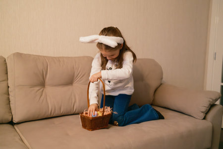 Young girl with bunny ears discovering Easter eggs in a festive basket