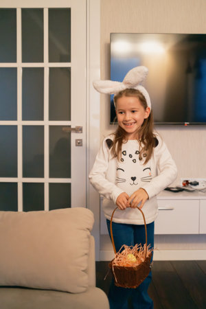 Smiling girl with bunny ears holding a basket during Easter celebration indoorsの写真素材