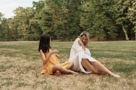Mother and daughter enjoying a playful day in the park outdoorsの写真素材