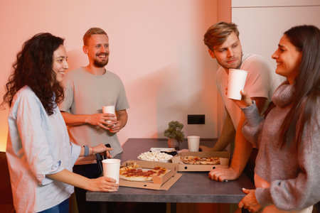 Group of friends enjoying pizza and drinks together at a cozy home gathering