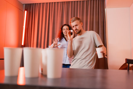 Friends enjoying a casual game with cups and laughter at a partyの写真素材