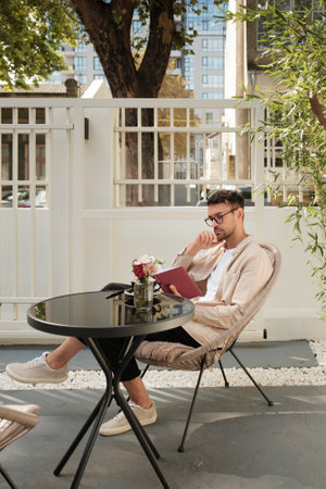 Man sitting in outdoor cafe with notebook and thoughtful expressionの写真素材