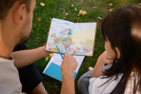 Father and daughter exploring a world map together in the park