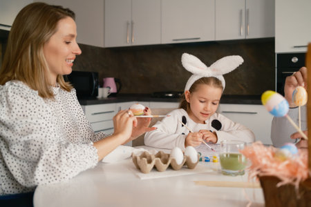 Mother and Daughter Painting Easter Eggs Together in a Festive Kitchen Settingの写真素材