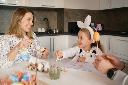 Family bonding together while painting Easter eggs in the kitchenの写真素材