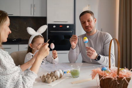 Family enjoying Easter activities and painting colorful eggs together at homeの写真素材
