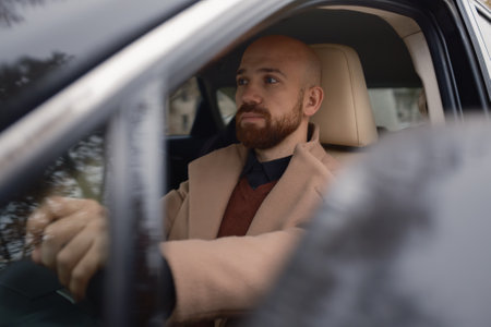 Man driving a modern car while looking ahead with a thoughtful expression