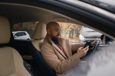 Man using smartphone inside a car during daylight hours on an autumn dayの写真素材