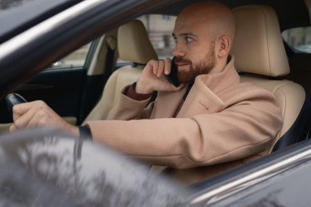 Business professional multitasking by phone while driving in a luxury carの写真素材