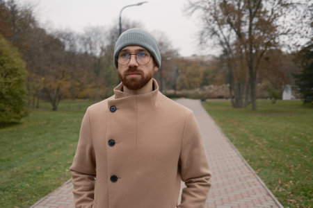 Man walks through a park wearing winter attire with an autumn backdrop