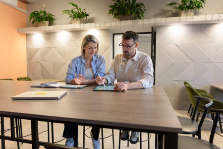 Two colleagues collaborating in a modern workspace with digital and physical toolsの写真素材