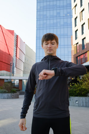 Man checking smartwatch during outdoor exercise in urban environmentの写真素材