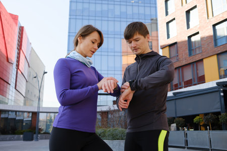 Couple checking fitness trackers while exercising outdoors in the cityの写真素材
