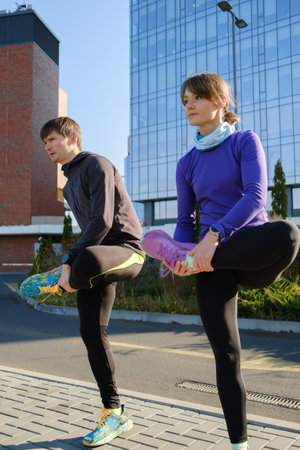 Couple stretching before outdoor run in urban environment on sunny dayの写真素材