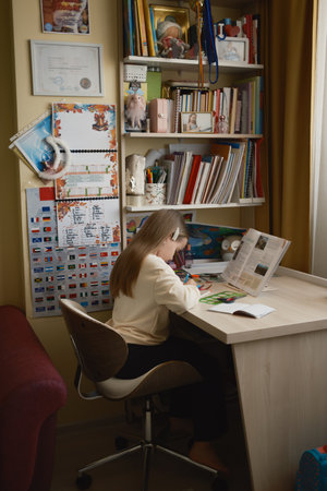 Young girl focused on homework at a tidy desk in her roomの写真素材