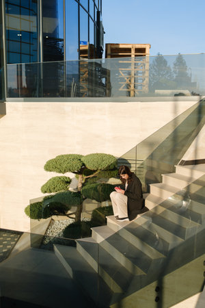 Business professional sitting on stairs in a modern architecture setting outdoorsの写真素材