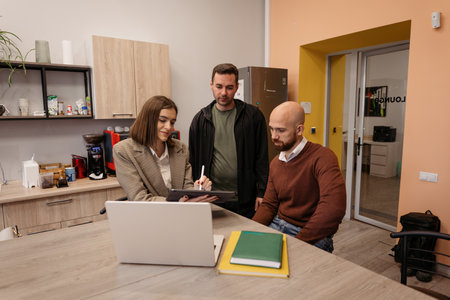 Group discussing a project at a desk in a modern office environmentの写真素材