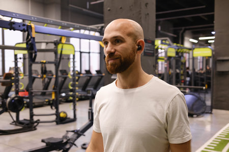 Man wearing earbuds at the gym surrounded by exercise equipmentの写真素材