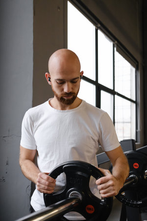 Man holding barbell weights during gym exercise in a fitness studioの写真素材