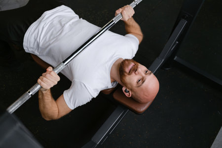 Focused man lifting weights on a bench in a gym for strength training