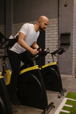Man focusing on cycling during an indoor gym training sessionの写真素材