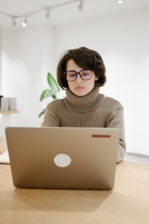 Focused Woman Using Laptop Indoors in Modern Workspace with Minimalist Design