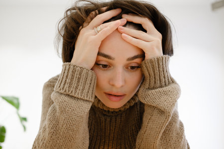 Portrait of a thoughtful woman with hands on her head wearing a sweater