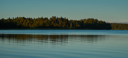 Blue water and sky. Lake. Reflection of forest in water.の写真素材