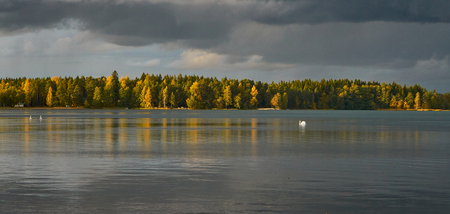 Autumn lake. Cloudy sky. Reflection on water.の写真素材