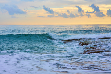 Beautiful tropical sunset on the beach of the sea with waves and foam.の写真素材