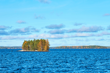 Island on lake with autumn trees and autumn forest on the background. Copy space.の写真素材