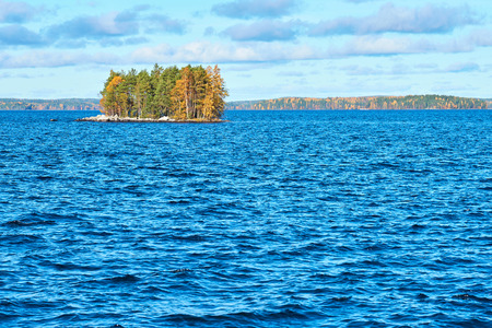 Island on lake with autumn trees and autumn forest on the background. Copy space.の写真素材