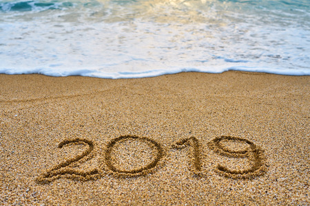 New Year 2019 is coming concept - inscription 2019 on a tropical sandy beach with waves and foam on a backgroung.の写真素材