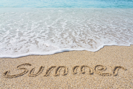 Summer inscription on a tropical sandy beach with blue sea, waves and foam on a background.の写真素材