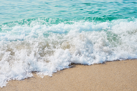 Waves with foam hitting sand on the tropical beach texture.の写真素材