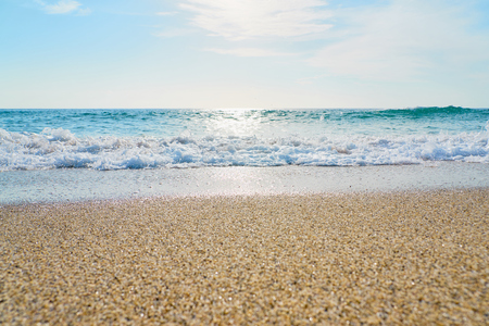 Sandy beach with waves and foam as a natural background with reflection of sunlight on water. Summer holiday concept.の写真素材