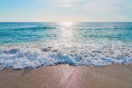 White foam close up on sandy beach with waves as a natural background with reflection of sunlight on water. Summer holiday concept.の写真素材