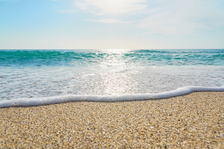 White foam close up on sandy beach with waves as a natural background with reflection of sunlight on water. Summer holiday concept.の写真素材