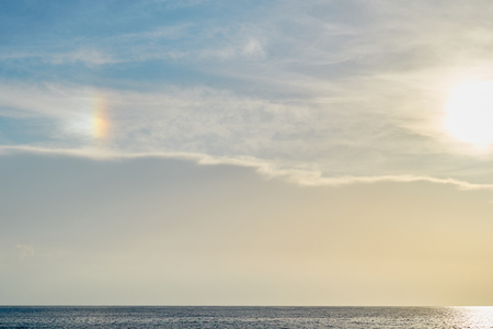 Blue cloudy sky with rainbow effect over the sea on a sunset as a natural background.の写真素材