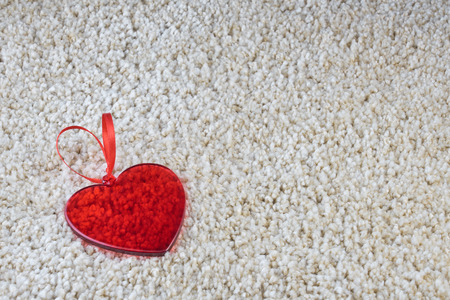 A red glass heart on a carpet love and Valentine concept. Copy space.の写真素材