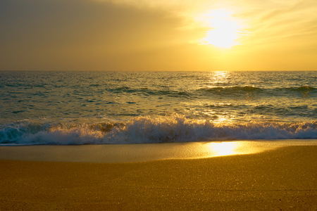 Tropical sandy beach. Sunset seascape. Waves with foam hitting sand.の写真素材