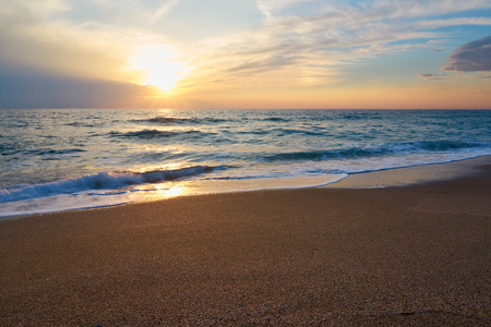 Tropical sandy beach. Sunset seascape. Waves with foam hitting sand.の写真素材