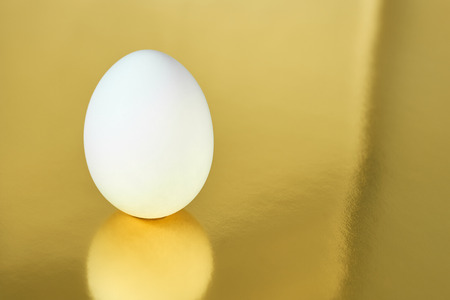 White egg with golden background. Easter concept.の写真素材